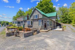a house with a green roof on a gravel driveway at Riverside Cabin with Private Fishing Access! in Pulaski