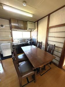 an empty kitchen with a wooden table and chairs at 灯ゲストハウス石巻 in Ishinomaki +6 photos