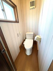 a small bathroom with a toilet and a window at 灯ゲストハウス石巻 in Ishinomaki
