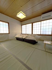 a bedroom with a bed in a room with windows at 灯ゲストハウス石巻 in Ishinomaki