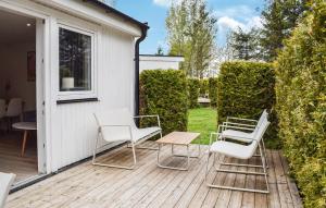a patio with white chairs and a table and chairs at Beautiful Home In Ystad in Ystad +18 photos