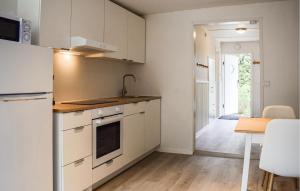 a kitchen with white cabinets and a table and a door at Beautiful Home In Ystad in Ystad