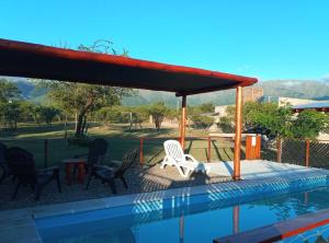 a swimming pool with a pavilion and chairs next to a swimming pool at cabañas sunrise in Merlo