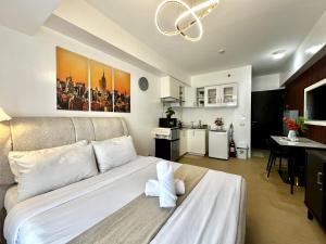 a bedroom with a large white bed and a kitchen at City View Studio Unit at Centrio Tower beside Ayala Mall in Cagayan de Oro