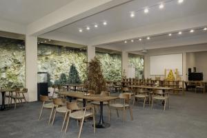 a conference room with tables and chairs and a screen at Chyanmu Hidden Village Retreat Near The Grand Canyon of Zhangjiajie and Yellow Dragon Cave With Local Culture Village Life Breakfast Quiet Wellness Escape for Urban Travelers Seeking Privacy and Peace in Zhangjiajie