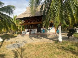 a resort building with a thatched roof and palm trees at Villa Neluc in San Bernardo del Viento
