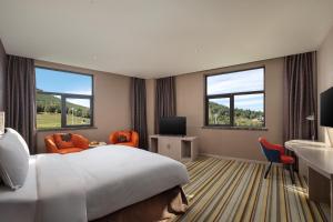 a hotel room with a large bed and two windows at Holiday Inn Express Changbaishan by IHG in Fusong