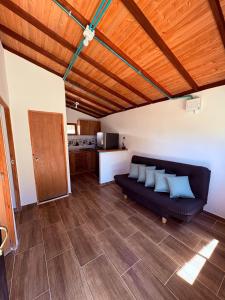 a living room with a black couch and a kitchen at Cabaña Alto Verde in Chiquinquirá