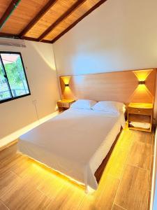 a bedroom with a large white bed with two lamps at Cabaña Alto Verde in Chiquinquirá