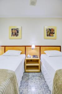 a hotel room with two beds and a nightstand between them at Hotel Domani in Guarulhos +141 photos