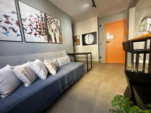 a living room with a blue couch with pillows at Flats Praia Uberlandia - Apt próximo ao Praia Clube - Area de lazer com Portaria 24 horas, piscina, academia, brinquedoteca, churrasqueira e áreas verdes para caminhadas in Uberlândia