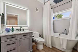 a white bathroom with a tub and a toilet and a sink at Loft Haven - Rooftop Terrace in Charlotte