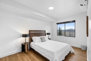 a white bedroom with a bed and a window at Airport Access with Stunning View A103 in Juneau