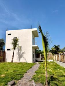 a white house with palm trees in front of it at Bamboo in El Paredón Buena Vista