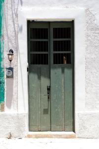a green door on a white building with a lamp at Casa Chultun Mérida Centro in Mérida
