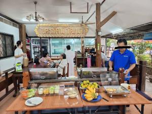 a man standing at a table with food on it at MG Guesthouse in Sukhothai