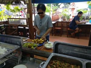 a woman preparing food on a table in a restaurant at MG Guesthouse in Sukhothai +35 photos