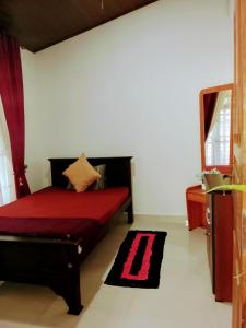 a room with a bed with a red bedspread at Luuna'S Hostel Sigiriya in Sigiriya