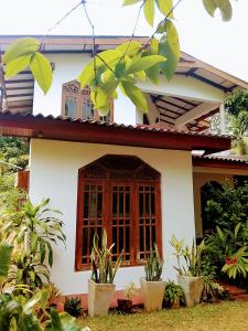 a white house with a window and some plants at Luuna'S Hostel Sigiriya in Sigiriya