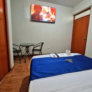 a room with a bed and a table with a tv on the wall at Hotel Delcor Suite in Piura