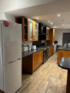 a kitchen with a white refrigerator and wooden cabinets at Haven Home 3 bedrooms near Sunderland City Centre Downstairs Shower with Toilet and Upstairs Bath with Toilet TV in each room in Sunderland +24 photos