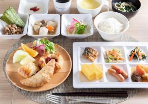 a table with plates of food and bowls of food at Super Hotel Sendai Hirose Dori in Sendai