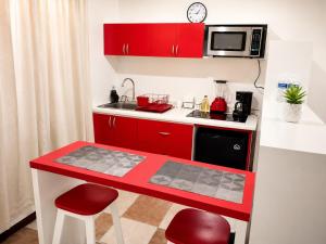 a small kitchen with red cabinets and a microwave at Casa Postal, Loft cerca del Centro, wifi rápido y estacionamiento in Oaxaca City +20 photos