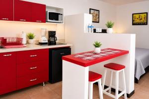 a small kitchen with red cabinets and a counter with stools at Casa Postal, Loft cerca del Centro, wifi rápido y estacionamiento in Oaxaca City