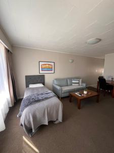 a bedroom with a bed and a couch and a table at Aorangi Motel in Fairlie