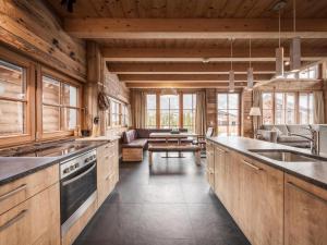 a kitchen with wooden cabinets and a living room at Modern chalet in the willow roof in Leutasch