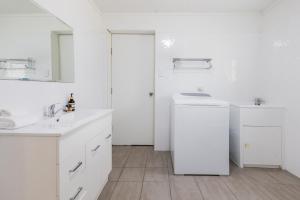 a white bathroom with two sinks and a mirror at A Lure - 100m to Main Beach in Agnes Water +26 photos
