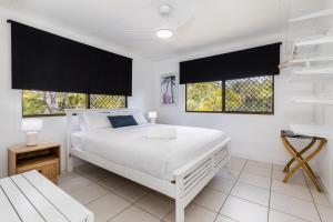 a white bedroom with a white bed and two windows at A Lure - 100m to Main Beach in Agnes Water