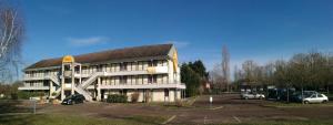 ein Gebäude mit Autos auf einem Parkplatz in der Unterkunft Premiere Classe Avallon in Sauvigny-le-Bois