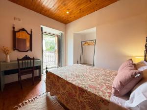 a bedroom with a bed and a desk and a mirror at Casa da Sequeirinha in Barreiros