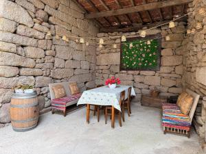 a patio with a table and chairs and a stone wall at Casa da Sequeirinha in Barreiros