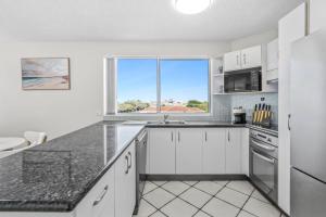 a kitchen with white cabinets and a large window at Seascape U7 in Golden Beach