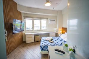 a room with a bed and a desk and a television at Voice activated studio condo unit at One Regis Megaworld, JK Modern Nest in Bacolod