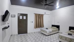a living room with two beds and a ceiling fan at F&D Homestay in Semporna