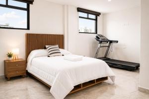 a white bedroom with a bed and a treadmill at Loft Ejecutivo San Martin Centro Wifi Tv 65 in San Martín Texmelucan de Labastida