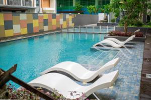 a swimming pool with two white chairs in the water at Voice activated studio condo unit at One Regis Megaworld, JK Modern Nest in Bacolod