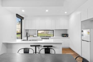 a white kitchen with a counter and stools at Sleek Contemporary Haven Geelong in Highton