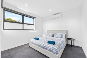 a white bedroom with a bed and a window at Sleek Contemporary Haven Geelong in Highton