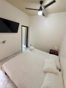 una camera da letto bianca con un letto grande e un ventilatore a soffitto di Casa Koru a Palenque