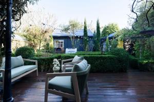 a patio with chairs and a couch and a house at Garden Cottage, Wellness Studio & Bike Shed in Winnaleah