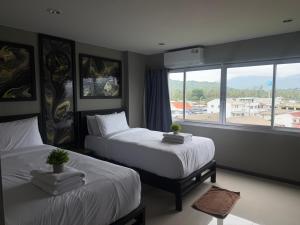 a bedroom with two beds and a large window at Amazing Inn Koh Phangan in Thong Sala
