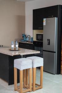 a kitchen with a counter with two stools and a refrigerator at Villa Miradie in Grand-Bassam