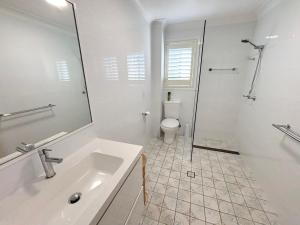 a white bathroom with a sink and a toilet at Jaspa - River Views - Bring your own linen in South West Rocks +17 photos