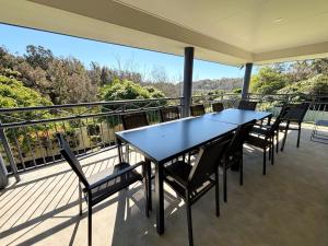 a black table and chairs on a balcony at Jaspa - River Views - Bring your own linen in South West Rocks