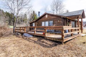 a wooden cabin with a large porch in a field at Ski Bowl Cottage! in Hunter