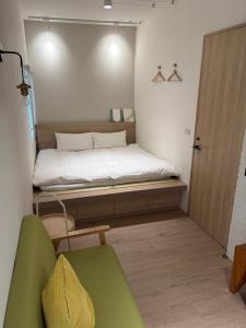 a small bedroom with a bed and a green chair at DayBreak 2 in Taitung City